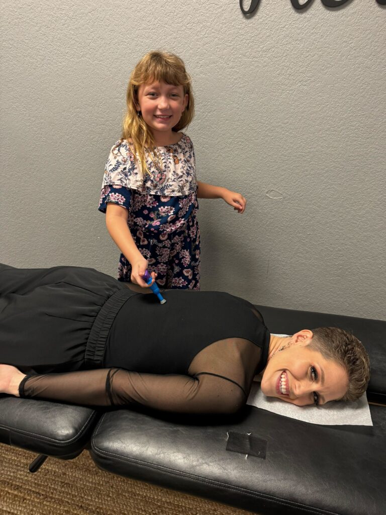 Dr. Stefanie laughing as a young child pretends to adjust her because we love teaching our chiro kids about chiropractic care for babies