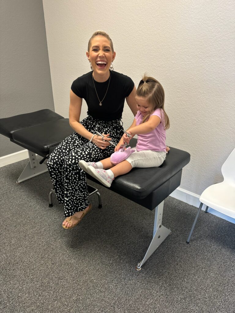 Dr. Stefanie laughing as a young child pretends to adjust her because we love teaching our chiro kids about chiropractic care for babies